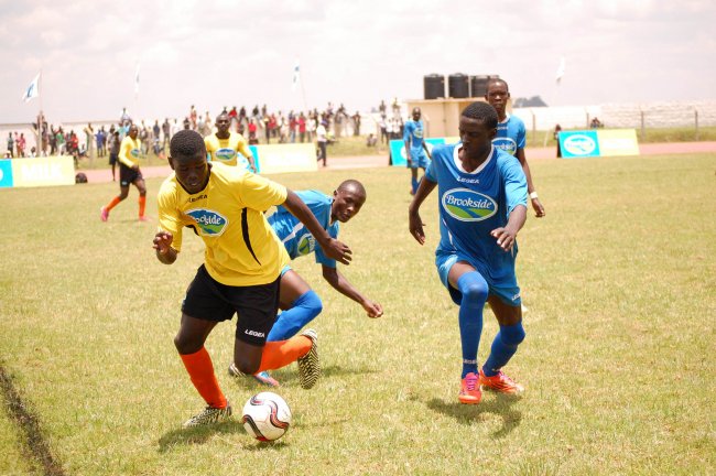 Francis Oite of St. Mary's Kitende (yellow) challenges Barding players. Barding are the new champions. 